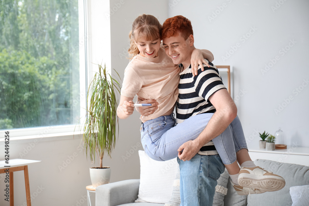 Happy young couple with pregnancy test at home