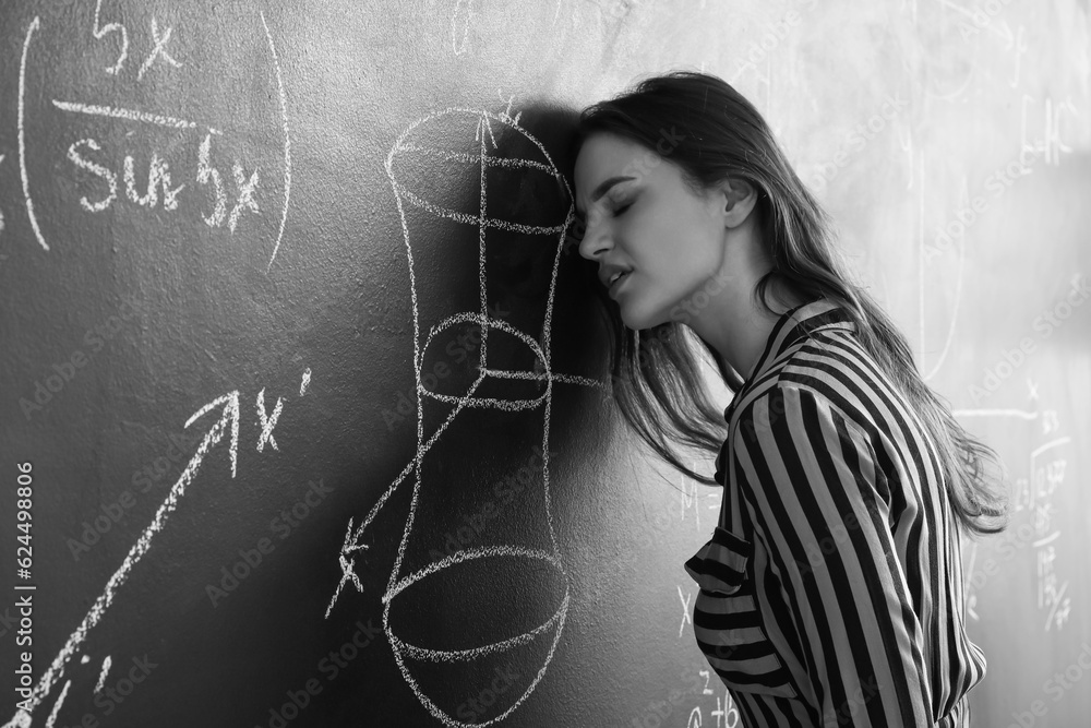 Stressed female Math teacher near blackboard in classroom