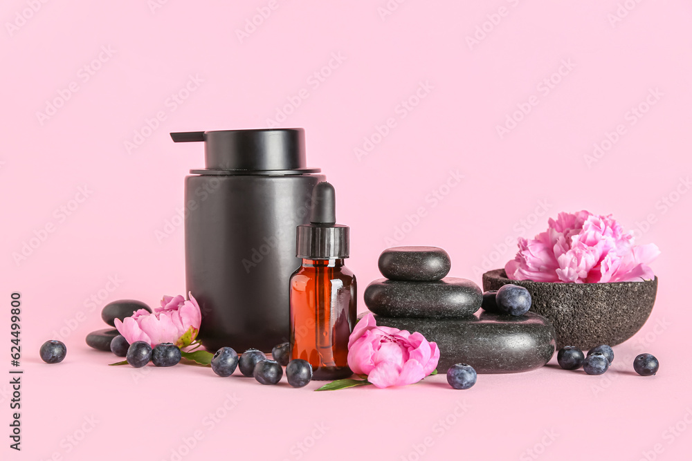 Composition with cosmetic products, spa stones, peony flowers and blueberry on pink background