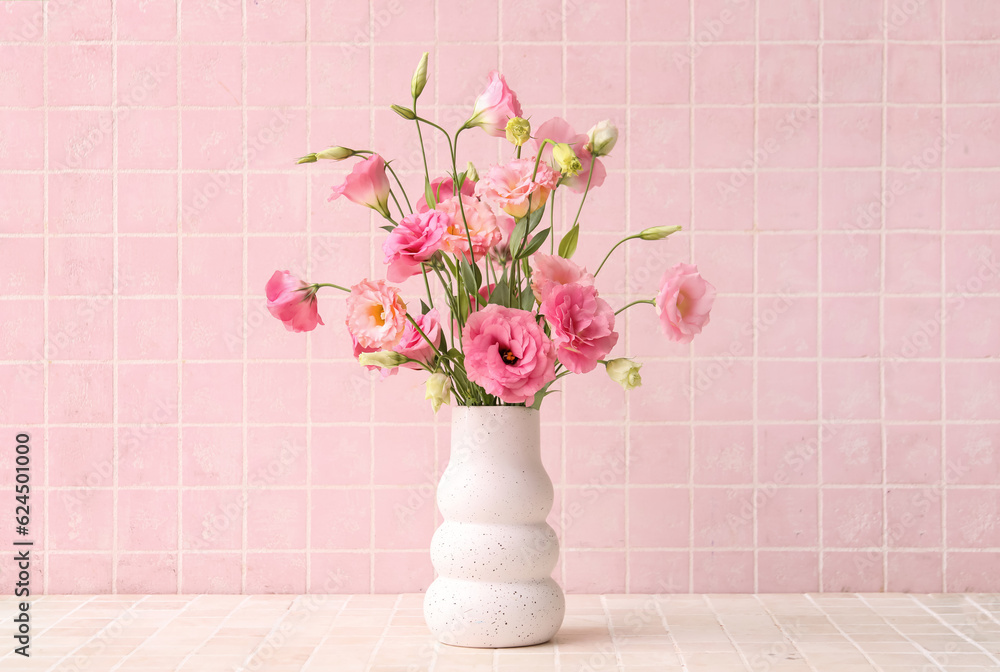 Vase with beautiful pink eustoma flowers on light tile background