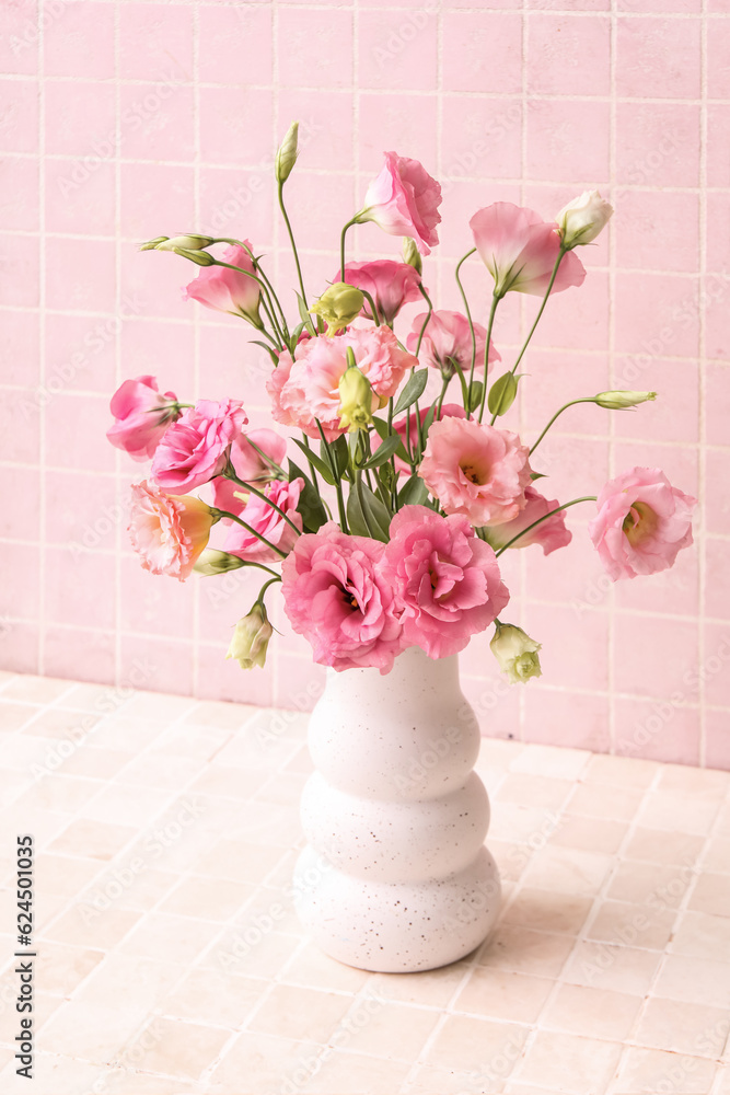 Vase with beautiful pink eustoma flowers on light tile background