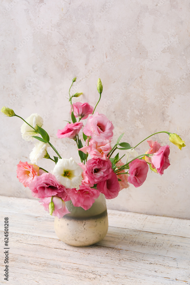 Vase with beautiful pink eustoma flowers on white wooden table