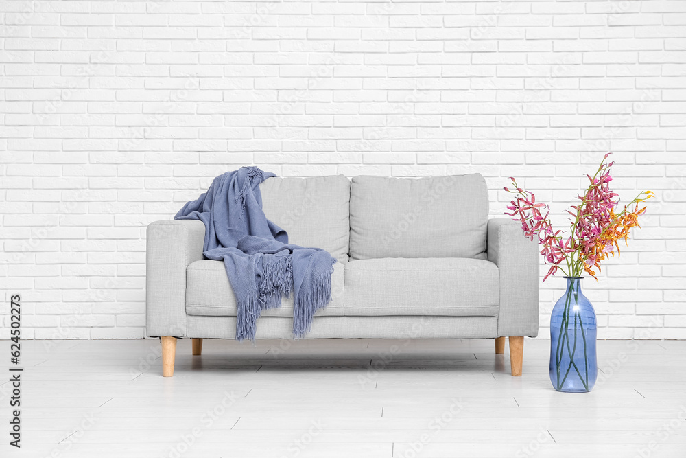 Interior of living room with sofa and vase near white brick wall