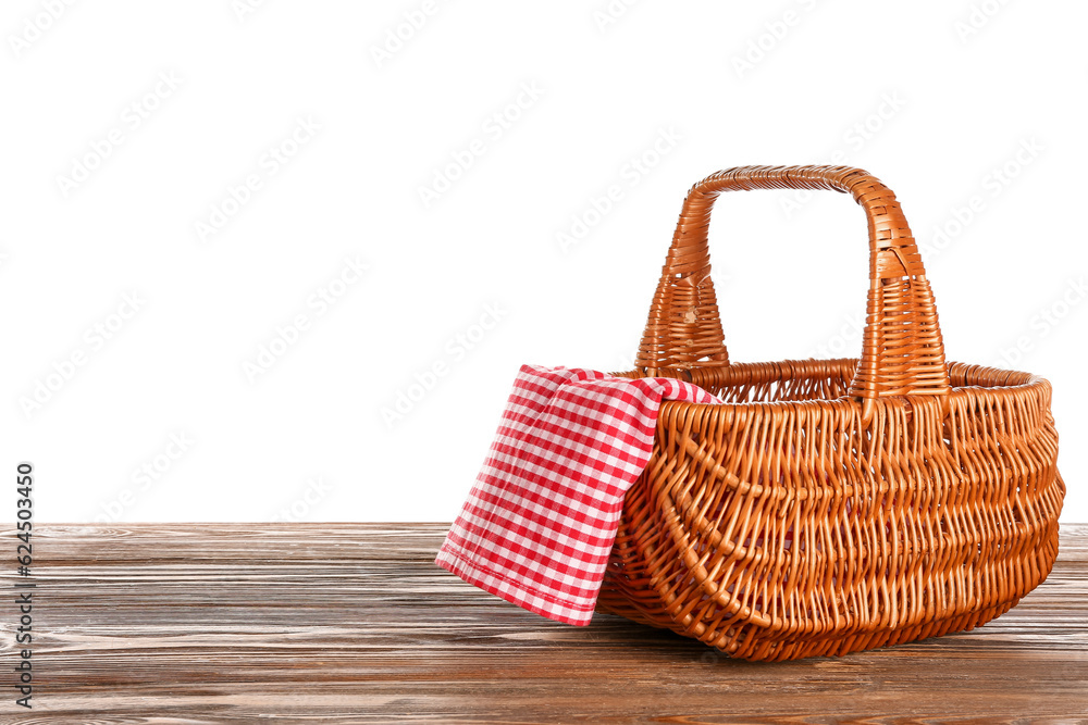 Wicker picnic basket with napkin on wooden table against white background