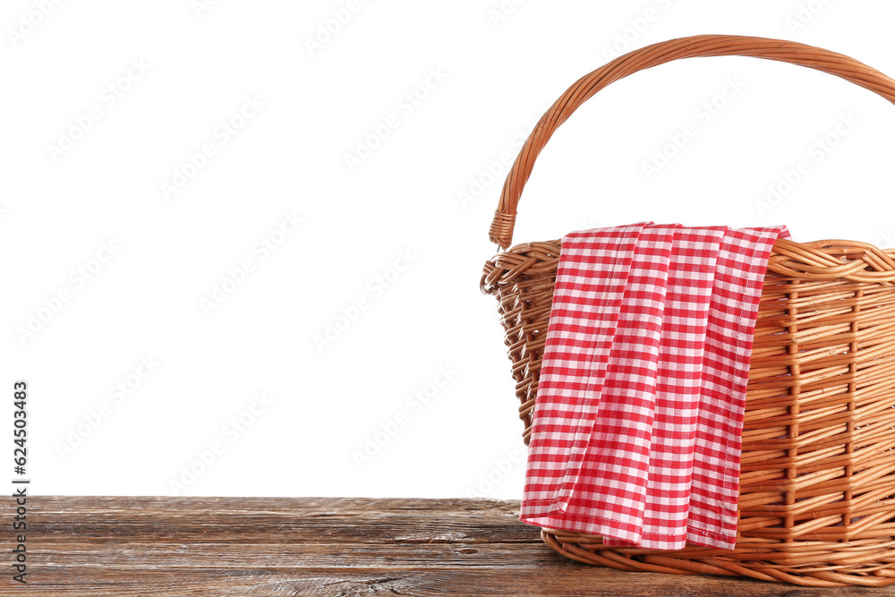 Wicker picnic basket and red checkered napkin on wooden table against white background