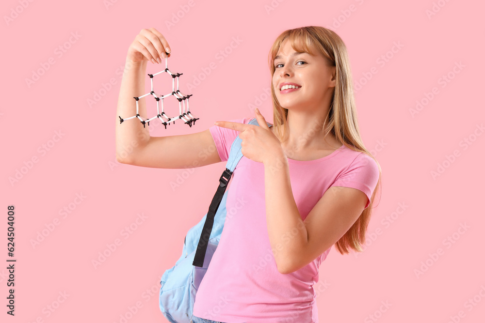 Female student pointing at molecular model on pink background