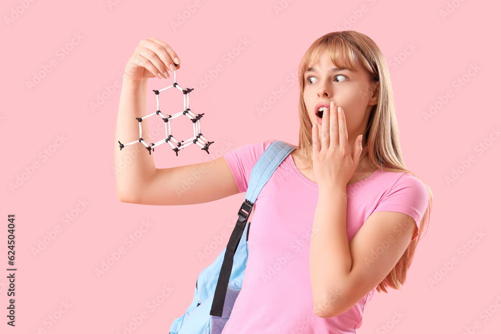 Shocked female student with molecular model on pink background