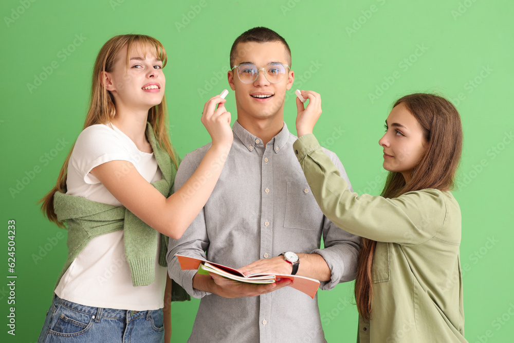 Female students with chalk pieces and their classmate on green background