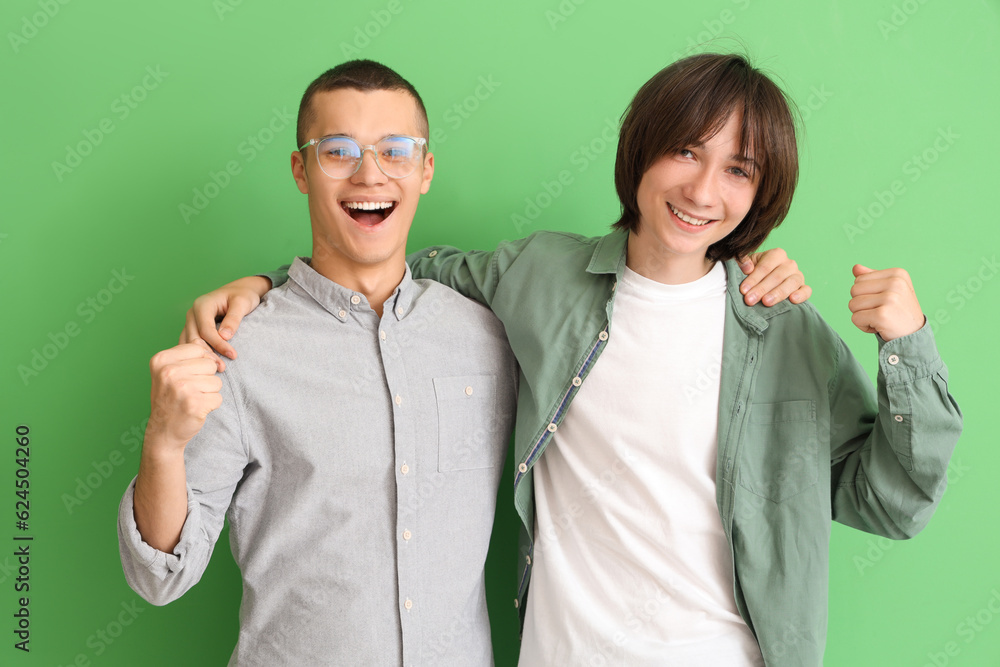 Happy male students hugging on green background