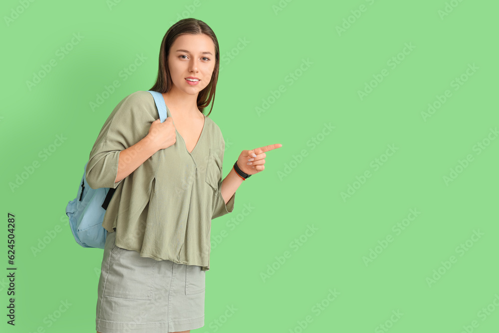 Female student pointing at something on green background