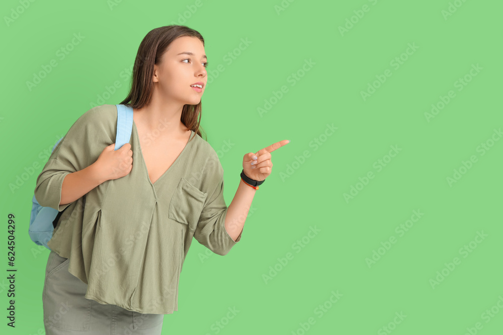 Female student pointing at something on green background