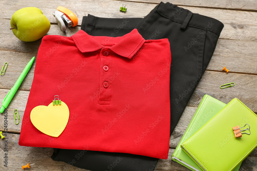 Different stationery with stylish school uniform and fresh apple on brown wooden background