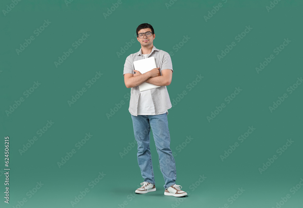 Male programmer with laptop on green background