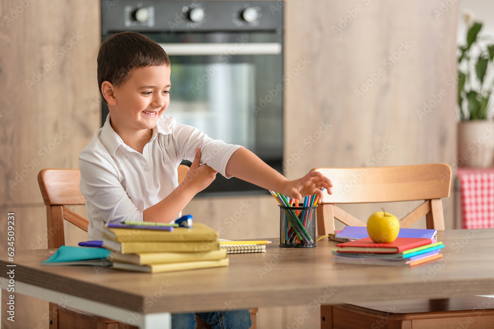 Cute little boy doing homework in kitchen