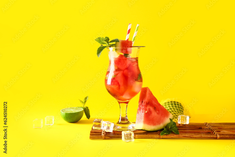 Glass of fresh watermelon lemonade with lime and mint on yellow background