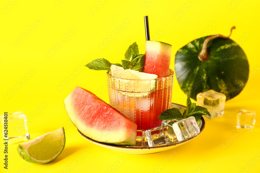 Glass of fresh watermelon lemonade with lime and mint on yellow background