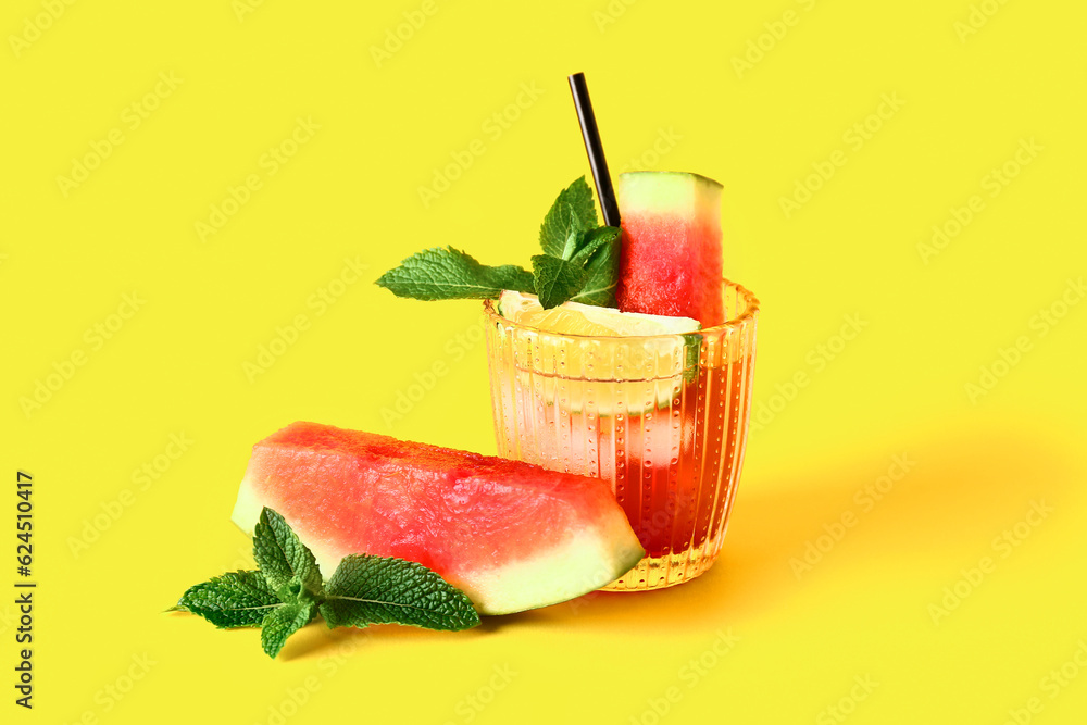 Glass of fresh watermelon lemonade with lime and mint on yellow background