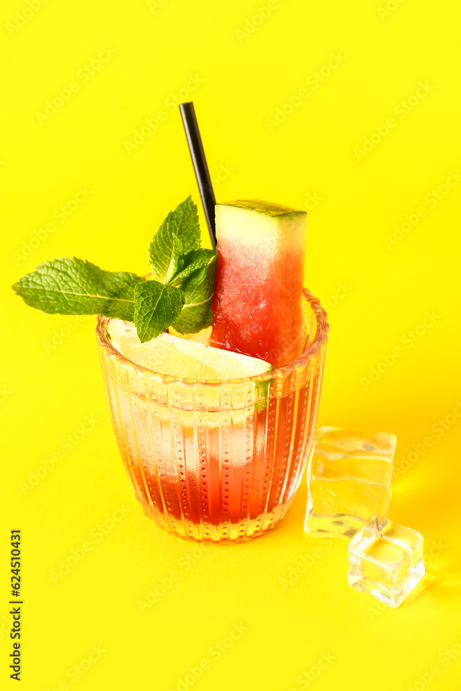 Glass of fresh watermelon lemonade with lime and mint on yellow background