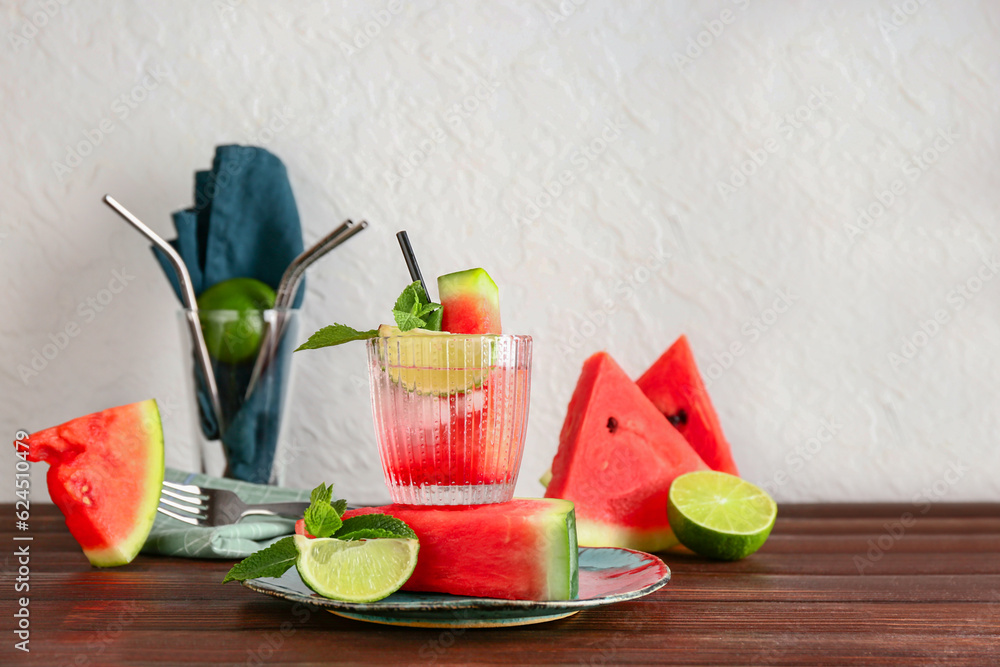 Glass of fresh watermelon lemonade with lime and mint on wooden table