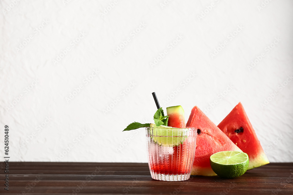 Glass of fresh watermelon lemonade with lime and mint on wooden table