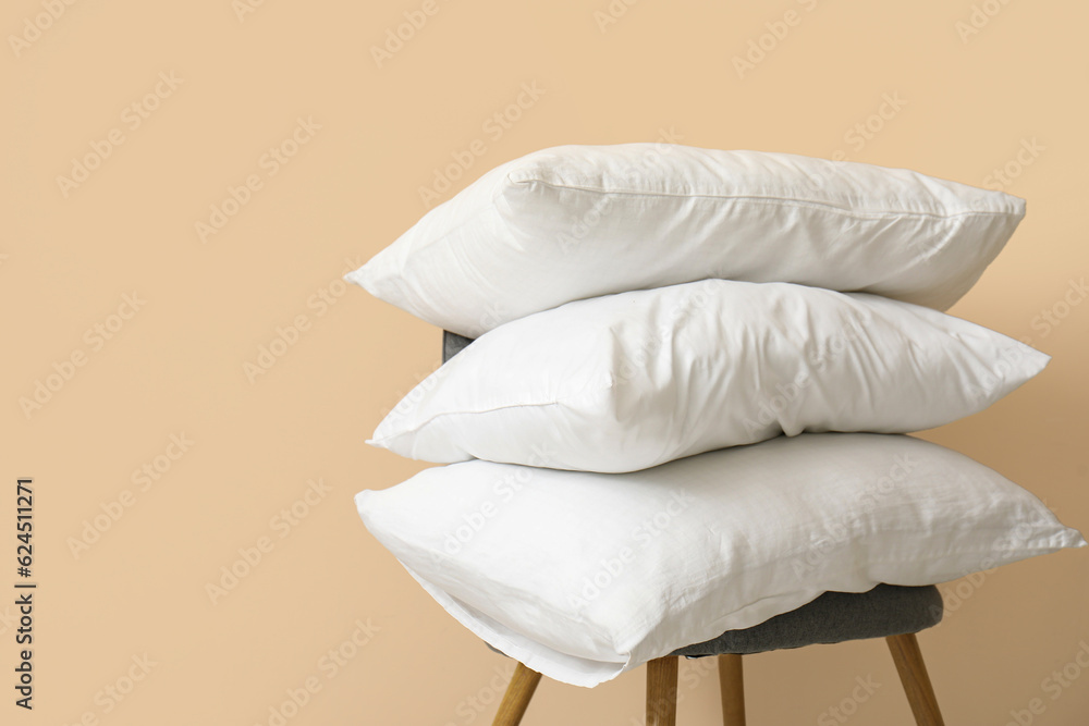 White pillows on chair near beige wall