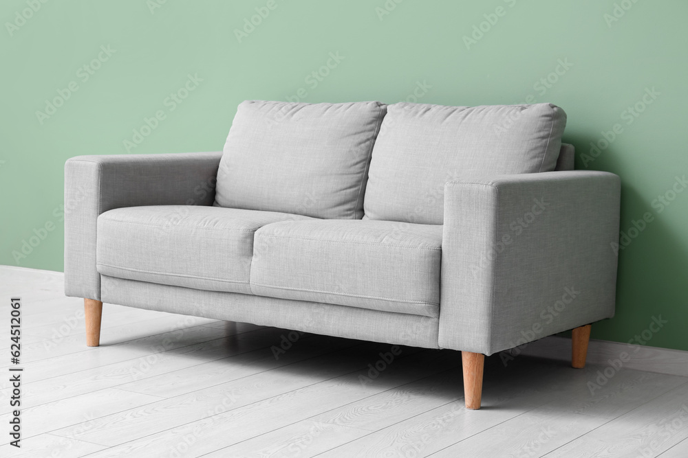 Cozy grey sofa near green wall