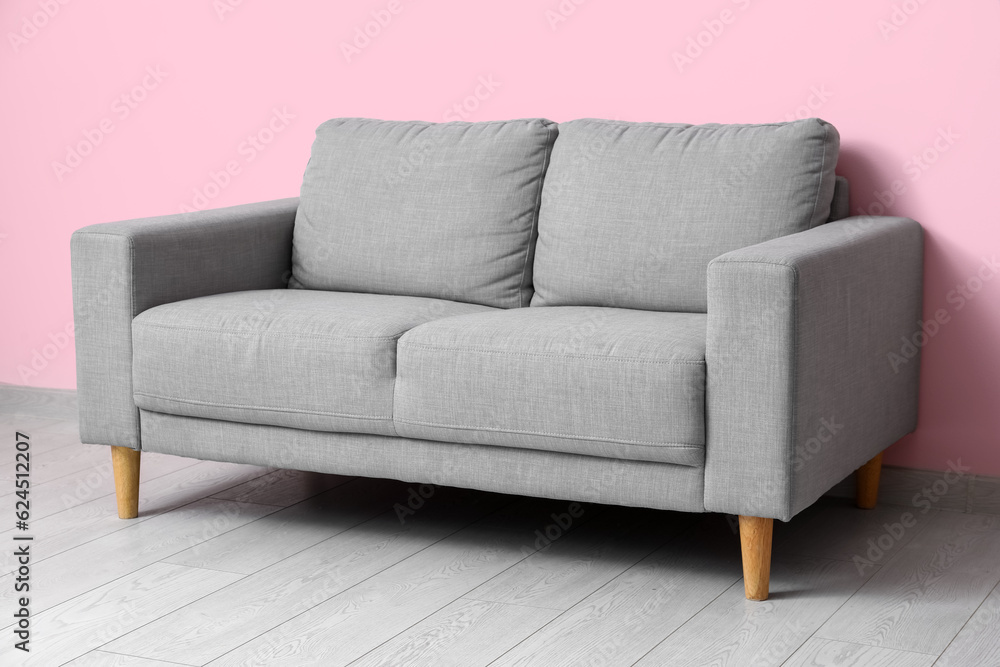 Cozy grey sofa near pink wall