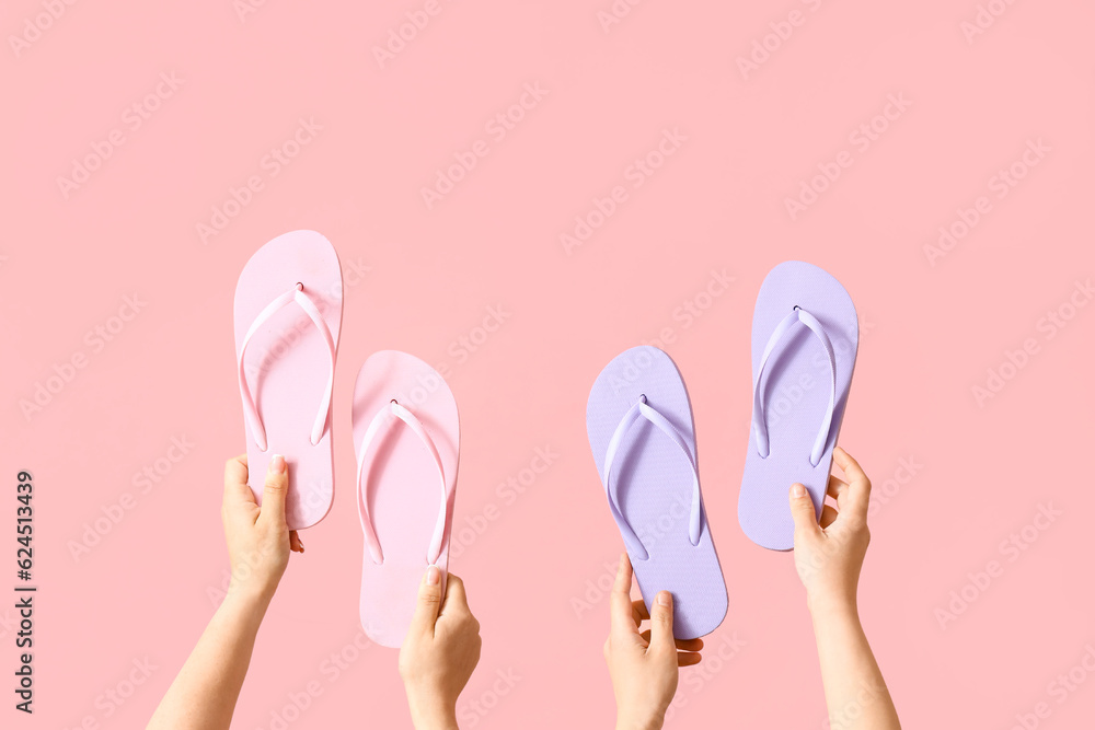 Many hands with different flip flops on pink background