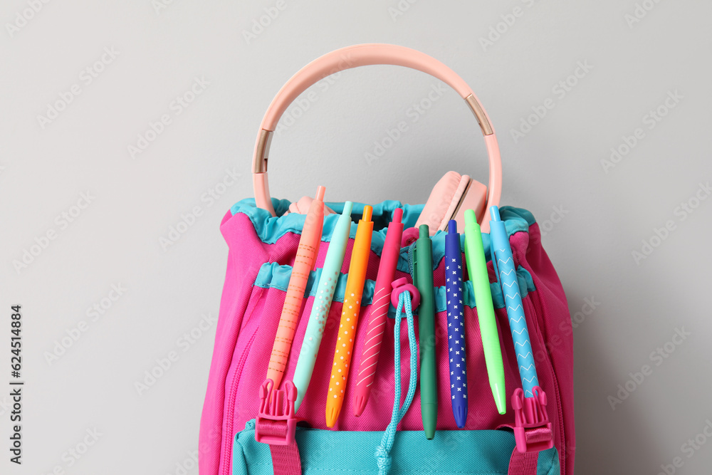 Colorful school backpack with different stationery on grey background