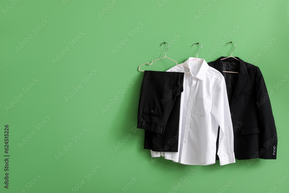 Stylish school uniform hanging on green wall in room