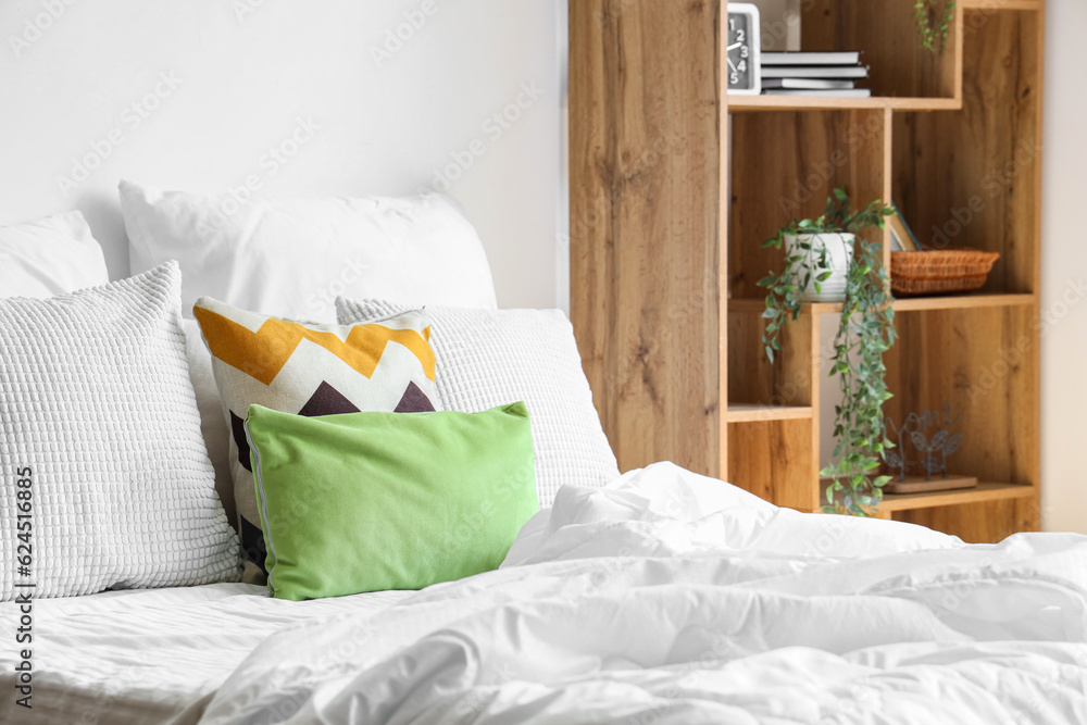 Cozy bed with white blanket and pillows in bedroom