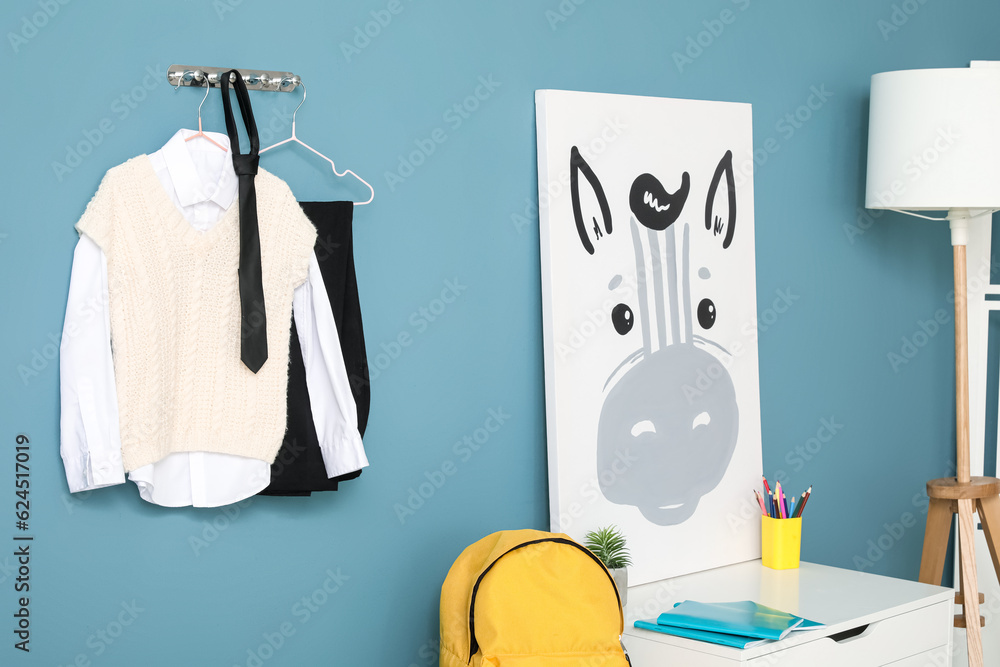 Stylish school uniform hanging on color wall and poster