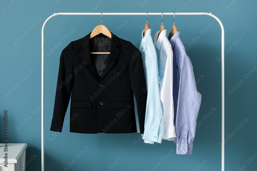 Rack with stylish school uniform against color wall, closeup