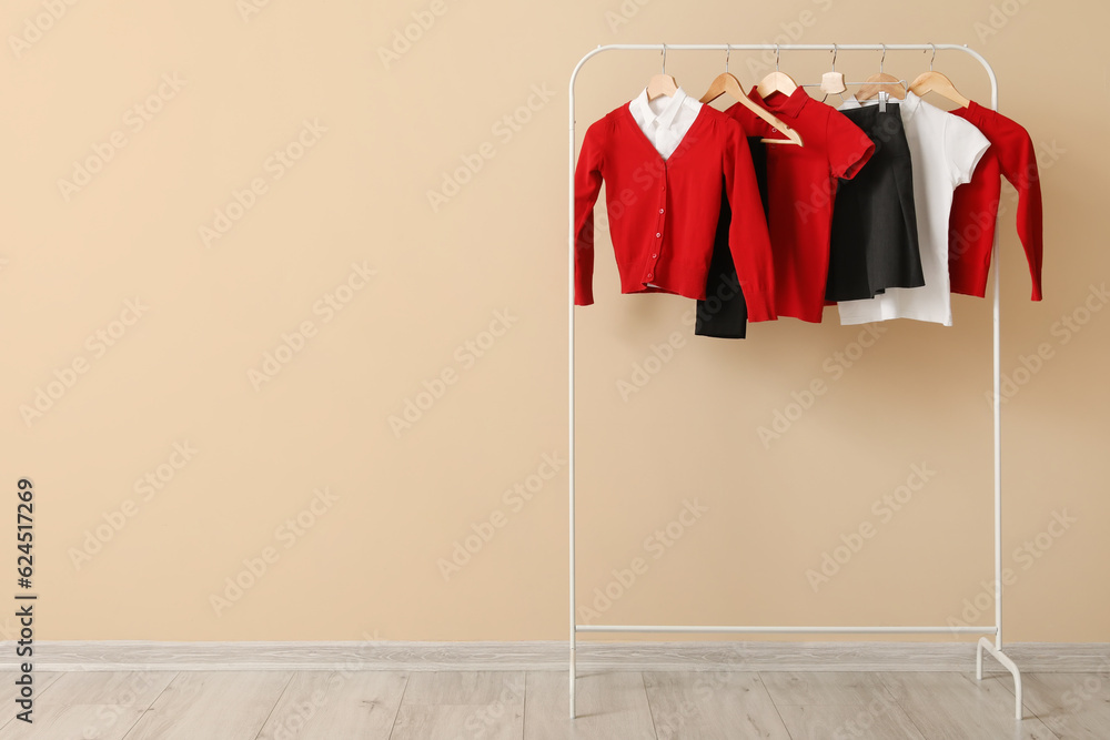 Rack with stylish school uniform against color wall