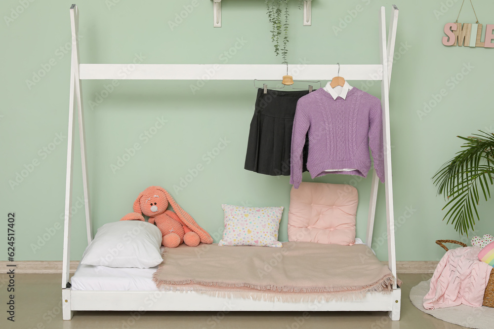 Stylish school uniform hanging on comfortable bed in childrens room