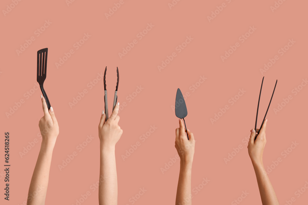 Female hands with spatulas and tongs on pink background