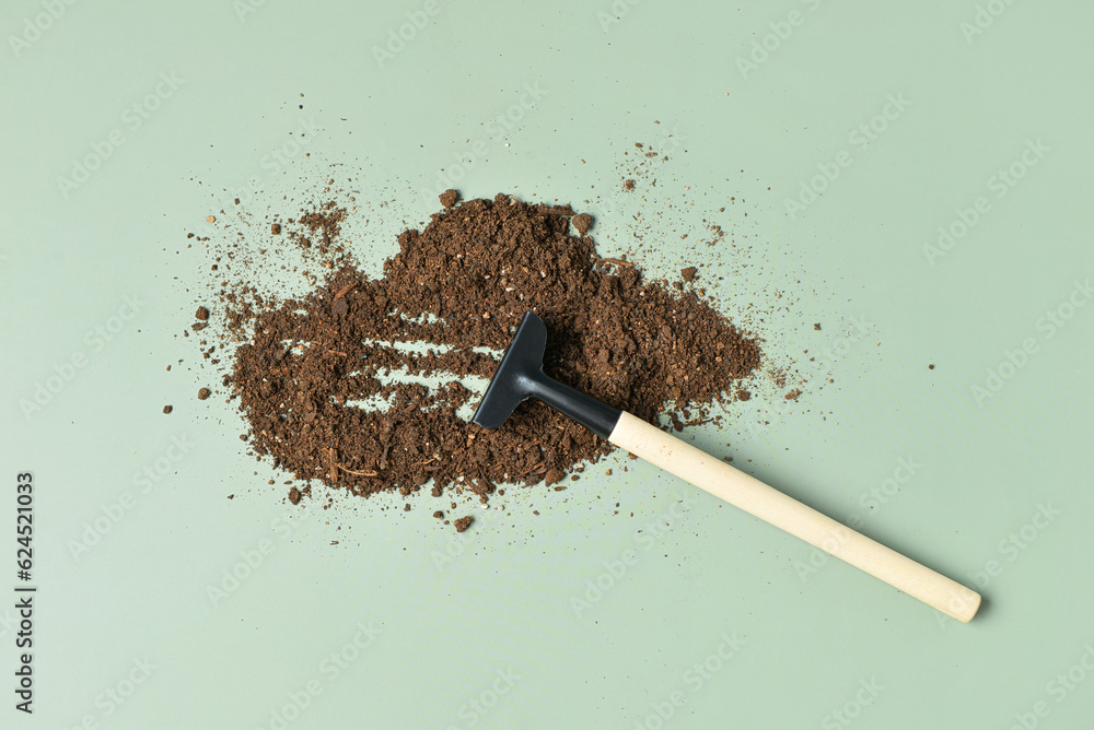 Gardening rake and soil on green background