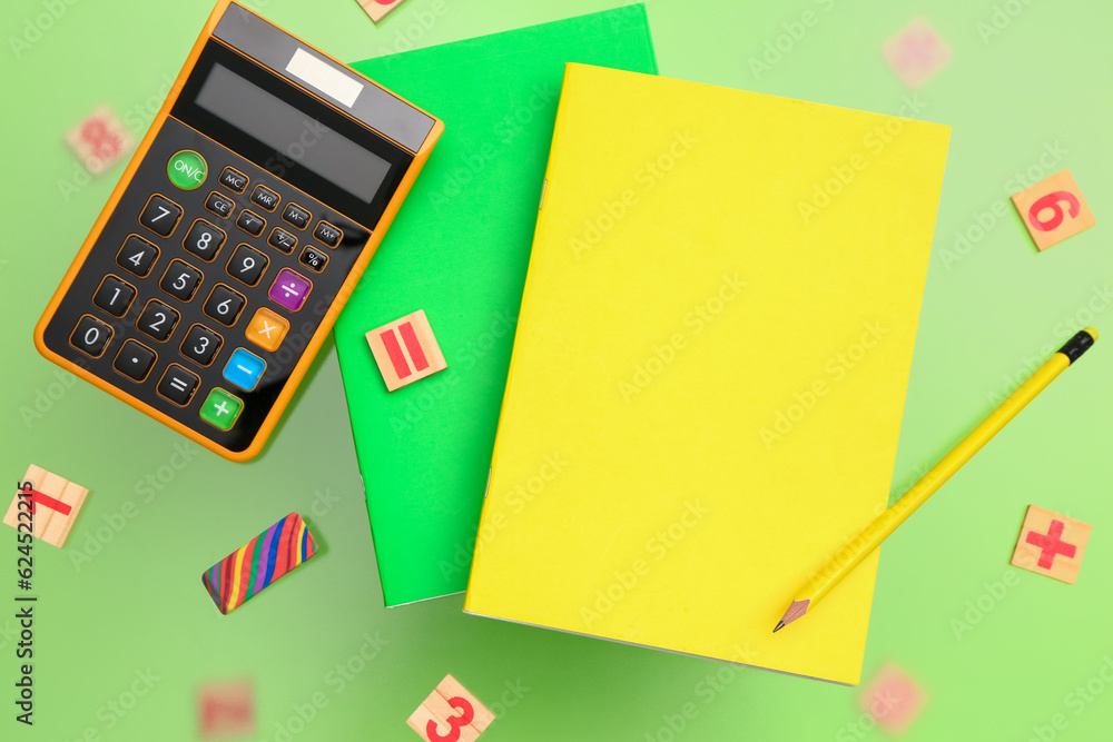 Calculator and notebooks with pencil on green background