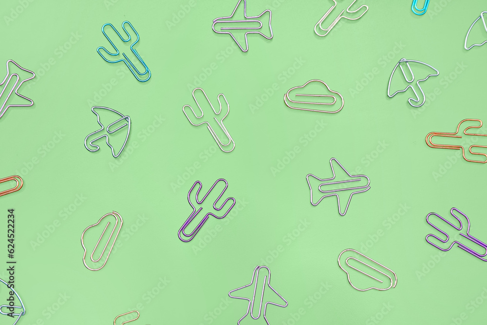 Colorful shaped paperclips on green background