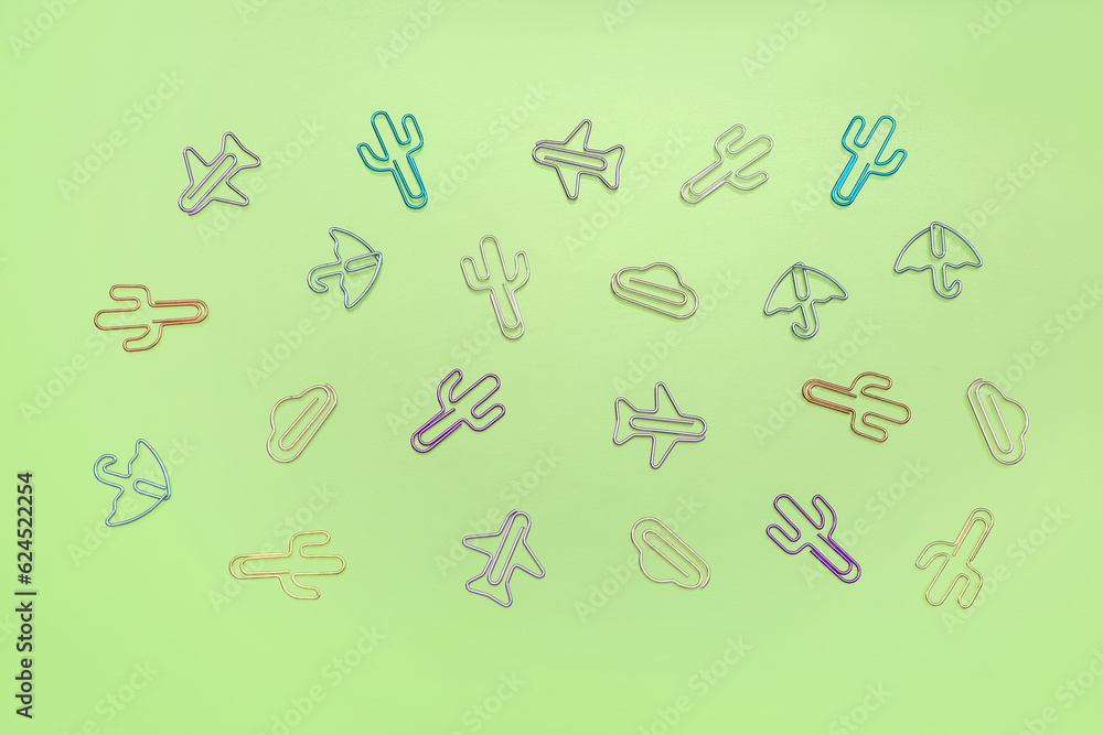 Colorful shaped paperclips on green background