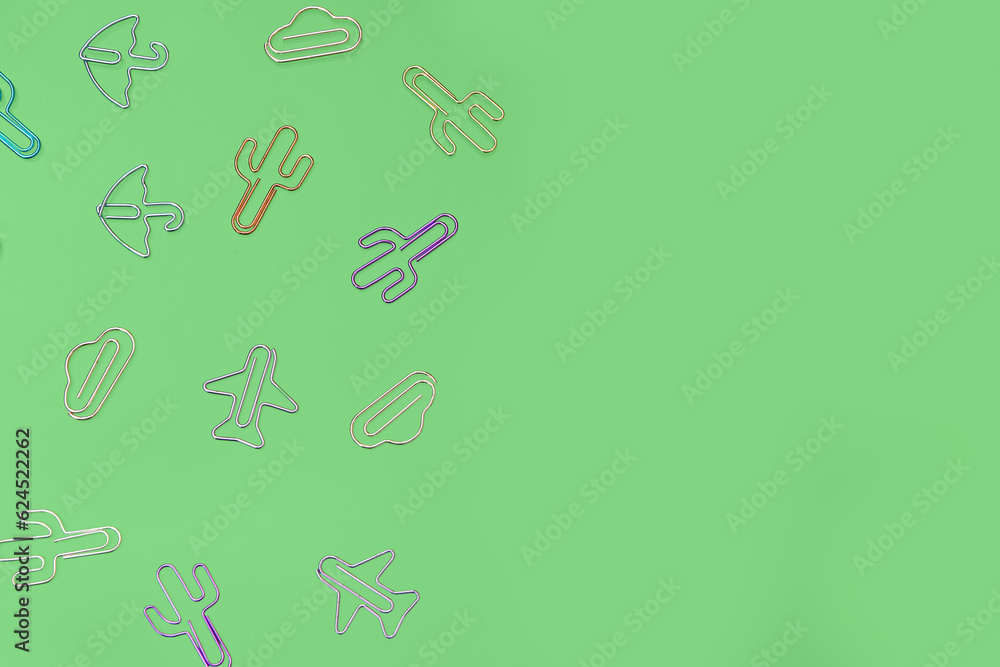 Colorful shaped paperclips on green background