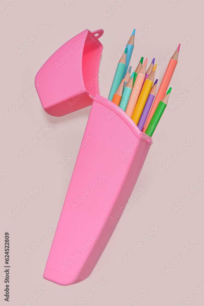 Case with colorful pencils on pink background