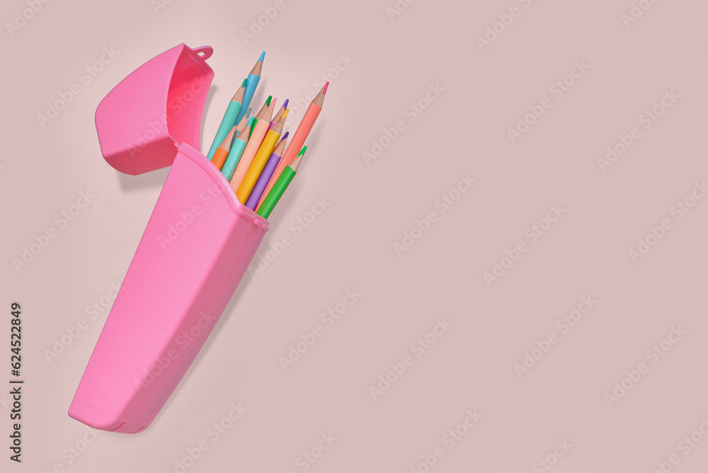 Case with colorful pencils on pink background