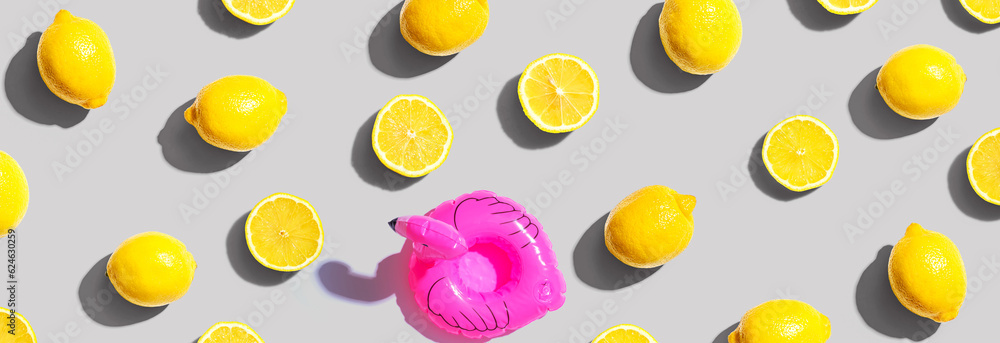 Summer concept with a pink flamingo float and lemons - flat lay