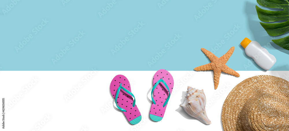 Summer concept with a straw hat, sunblock, starfish, beach sandals and shell overhead view