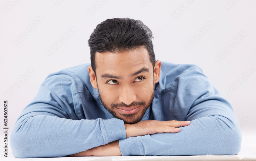 Thinking, dreaming and young man in a studio resting on his arms with a contemplating facial express