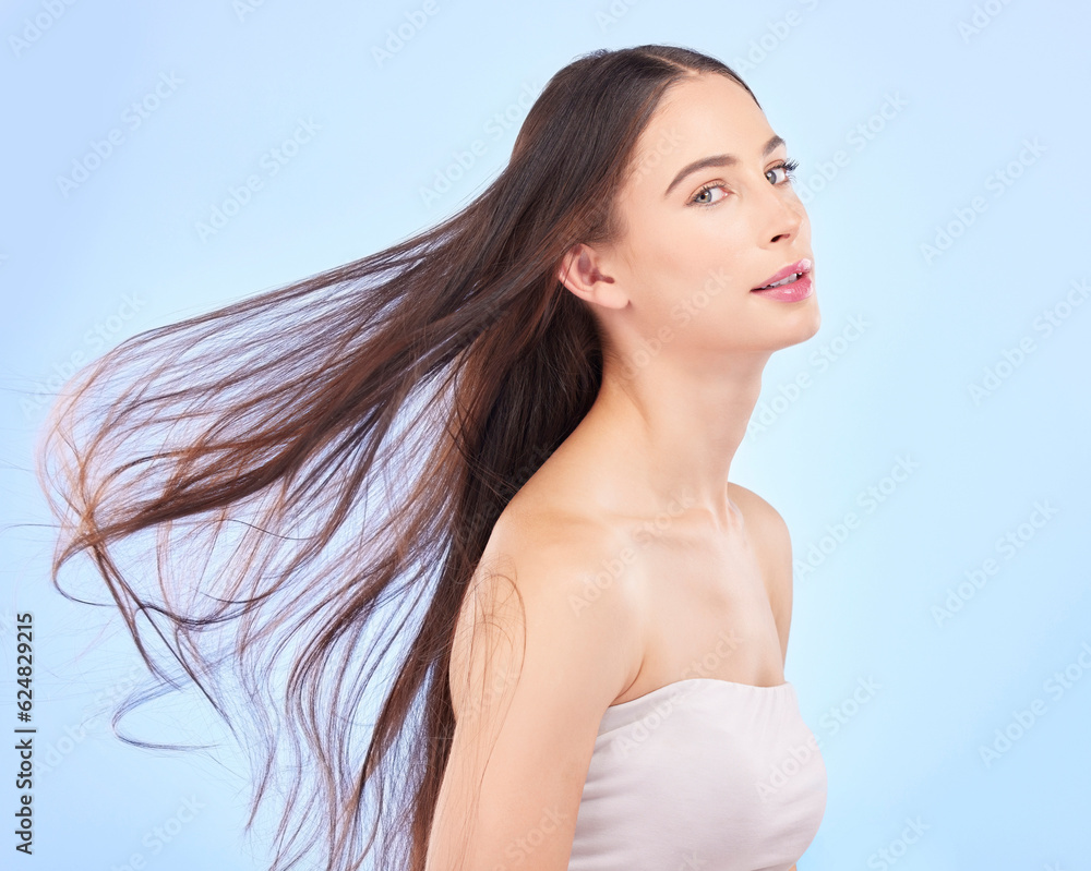 Portrait, hair and wind with a model woman in studio on a blue background for skincare or keratin tr