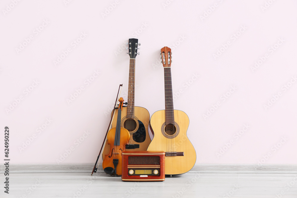 Different musical instruments and retro radio receiver near light wall