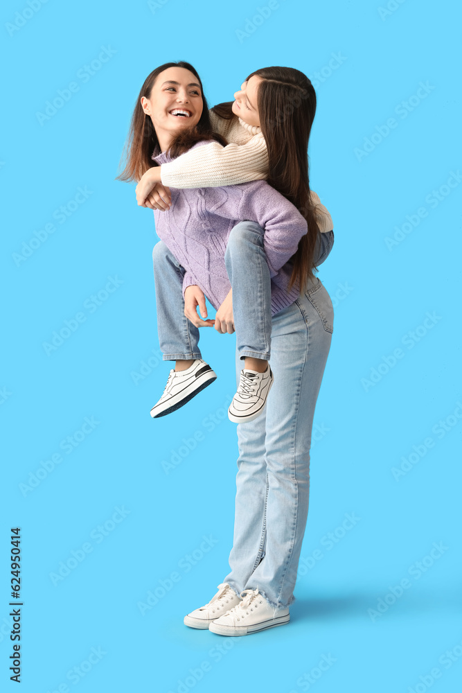 Little girl and her mother in warm sweaters on blue background