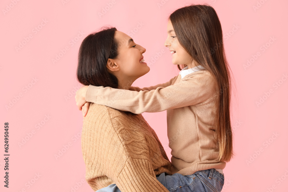 Little girl and her mother in knitted sweaters on pink background